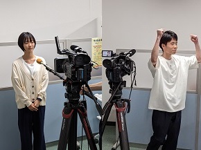 インタビューを受ける学生(達成感からガッツポーズ(右))