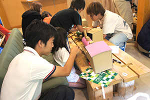 色塗りを手伝う学生” class=